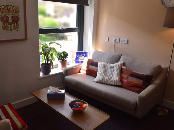 Room 2, showing a therapist's chair and client's sofa with a coffee table in the middle and tissues and fidget toys resting on top