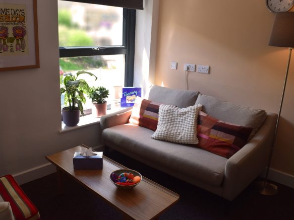 Room 2, showing a therapist's chair and client's sofa with a coffee table in the middle and tissues and fidget toys resting on top