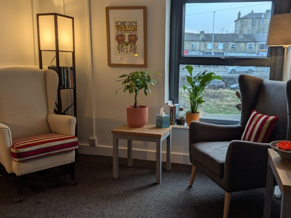 An image of one of the counselling rooms in Wharf St. Practice, featuring two chairs in a warmly lit room with several plants.